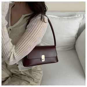 Close-up of wine red PU leather baguette bag with elegant gold clasp and fixed shoulder strap