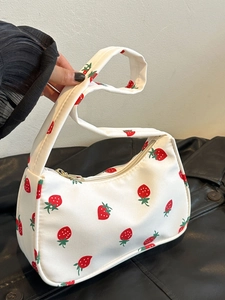 Close-up of a white nylon shoulder bag with red strawberry pattern and golden zipper