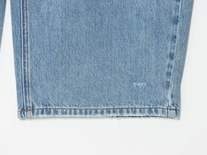 Vista macro dell'orlo in denim azzurro con cuciture fini e dettagli invecchiati