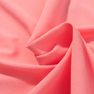 Gros plan sur la texture du tissu crêpe rose avec un grain fin et un drapé doux
