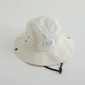 Détail du chapeau beige pour enfant avec écusson Go violet et boutons-pression latéraux
