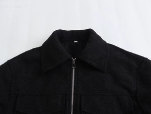Détail d'une veste en tweed noir avec fermeture éclair métallique et col à revers classique