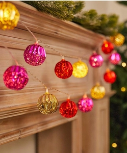 Close-up of faceted LED ball string lights on a festive fireplace with pine needles