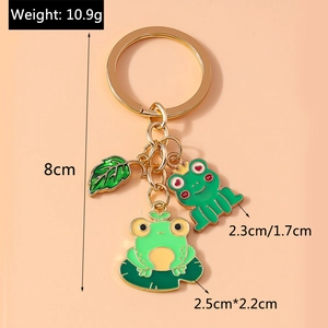 Detail view of cute green frog pendants on a golden keychain with size dimensions