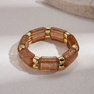 Detailed macro view of geometric elastic bracelet with brown glitter beads and gold spacers