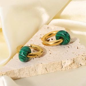 Detail of 18K gold earrings with green malachite stone beads on beige silk fabric