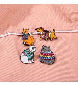 Detail of four colorful animal enamel pins featuring fox and cat on pink denim fabric
