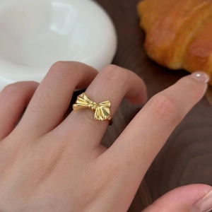 Detailed view of elegant gold bow ring worn on finger with high-quality polished finish