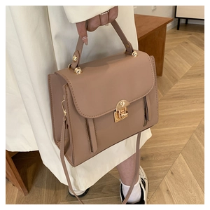 Detail of minimalist beige crossbody bag featuring golden hardware and top handle