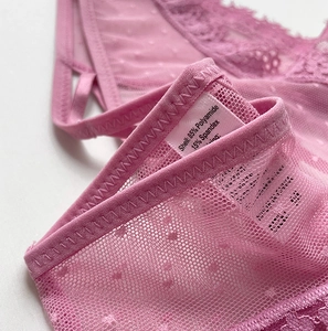 Détail de la culotte en dentelle rose montrant l'étiquette 85% Polyamide et 15% Élasthanne