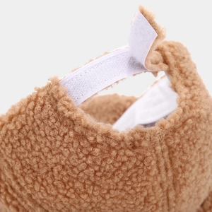 Detailed view of brown teddy fleece hat with white adjustable velcro strap at the back