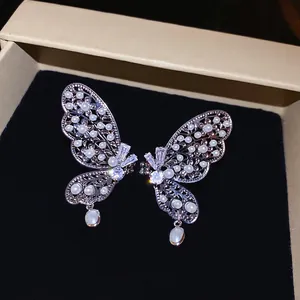 Clips d'oreilles élégants ailes de papillon avec perles et zircons dans un écrin à bijoux