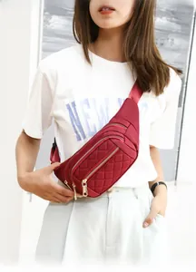 Detail of burgundy quilted crossbody waist bag with three zipper compartments and gold hardware