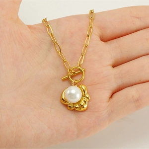 Close-up of gold paperclip chain necklace with OT buckle and white pearl pendant