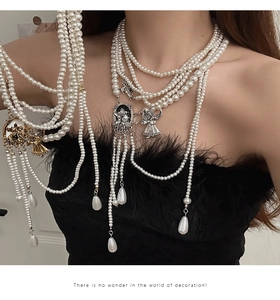 Detail view of multilayer pearl necklace with vintage silver and gold angel pendants