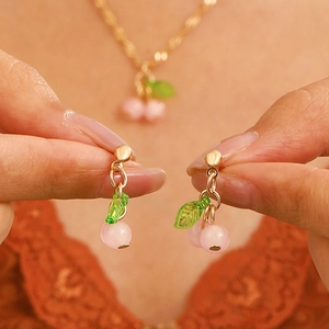 Pink resin cherry jewelry set featuring a sweet necklace and stud earrings with gold accents