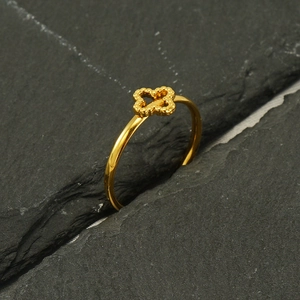 Minimalist 18k gold plated four-leaf clover ring set in a textured dark rock crevice