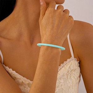 Détail d'un bracelet en acrylique vert menthe au poignet avec dentelle élégante en fond