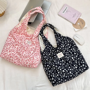 Detail of pink and black heart leopard print tote bags with woven labels on fabric