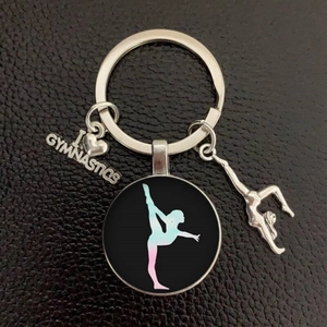 Detail of I Love Gymnastics metal keychain with gymnast charms on black leather texture