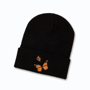 Gros plan sur un bonnet en tricot noir avec broderie détaillée de papillons oranges