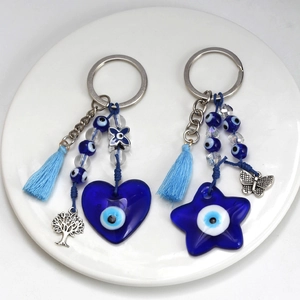 Close-up of blue evil eye keychains with heart and star glass charms and silk tassels