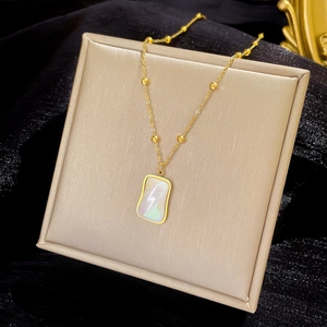 Macro shot of rectangular pearlescent pendant necklace on beige jewelry display cushion