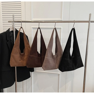 Close-up of four minimalist suede tote bags in various autumn brown and black tones