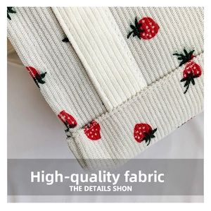 Detail of corduroy bag fabric with red strawberry prints and fine stitching