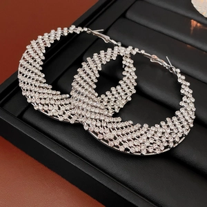 Close-up of silver hoop earrings with shimmering white crystals on a black stand