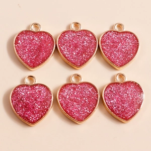 Detailed view of six gold heart-shaped pendants filled with vibrant rose red glitter