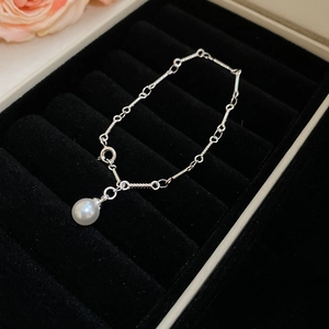 Close-up of a silver bamboo chain bracelet with a white pearl pendant on a velvet box