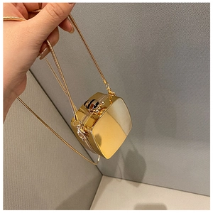 Detail of a mini gold mirrored hard case bag with a decorative bee clasp and chain