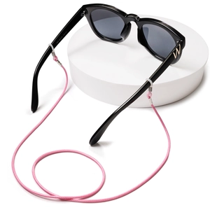 Pink woven lanyard for kids sunglasses on a minimalist white stand with black frames
