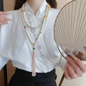 Detailed view of layered pearl body chain with crystal lotus tassel on a model