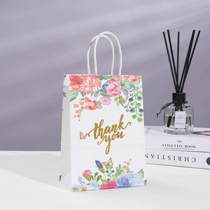 Close-up of white floral gift bag with gold thank you text and white rope handles