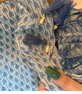 Detail of blue cotton linen scarf featuring arrow pattern and tassels with wooden beads