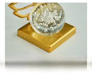 Close-up of crystal ball on a wide matte gold metal base with stable decorative stand