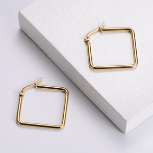 Minimalist gold square hoop earrings in polished titanium steel on geometric display