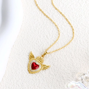 Macro detail of gold-plated necklace featuring a red heart pendant with white zircons