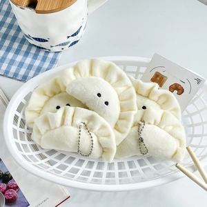 Detailed view of three cute dumpling plush keychains in a white basket on a plaid mat