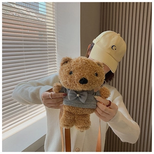 Close-up of a cute plush bear crossbody bag with a bow tie outfit held by a model