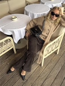 Chic autumn style showing camel knit cardigan paired with brown trousers and a quilted bag