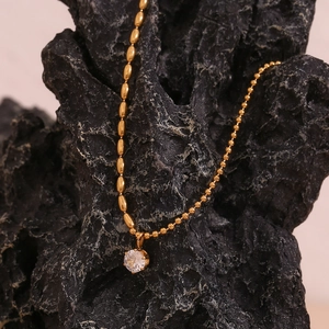 Dettaglio macro della catena a sfere placcata oro 18K e pendente in zircone su minerale