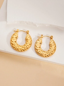 Detailed close-up of vintage gold hoop earrings with irregular hammered lava texture
