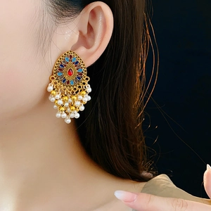 Détails de boucles d'oreilles vintage dorées avec motifs émaillés et pampilles de perles