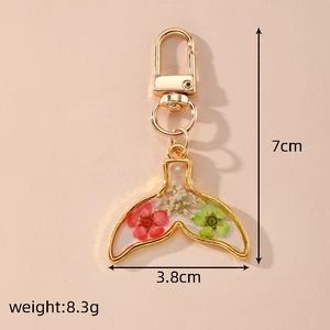 Detailed size view of handmade resin fish tail keychain with dried flowers and gold hook