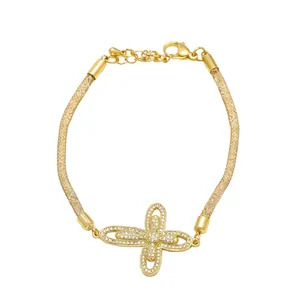 Detalle de pulsera de malla dorada con colgante de cruz de circonitas brillantes