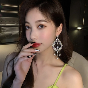 Exaggerated silver drop earrings with floral rhinestones worn by a model in close-up