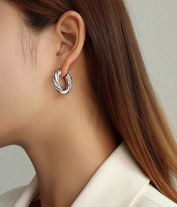 Close-up of a silver twisted hoop earring on a model for a minimalist aesthetic